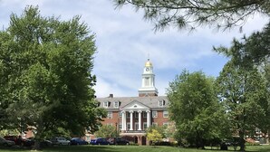A building with a central tower and columns, surrounded by a well-maintained lawn and parked cars. - Perfect 2 BR Condo in Princeton w Parking  (PRINCETON)