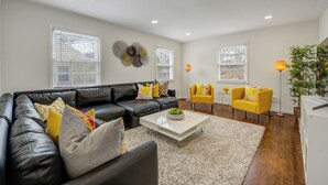 A modern living room with a black leather sofa, a white coffee table, a yellow armchair, and a small side table with a lamp. - Perfect 2 BR Condo in Princeton w Parking  (PRINCETON)