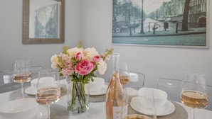 A dining table set with white plates, glasses, and a bottle of wine, accompanied by a vase of pink and white flowers. - Perfect 2 BR Condo in Princeton w Parking  (PRINCETON)