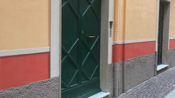 Un edificio con una porta verde, una targa che recita "CASA ITALIA" e il numero "23" sopra la porta.