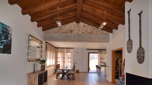 Amplia sala de estar con techo de madera alto, pared de piedra y comedor con mesa y sillas.