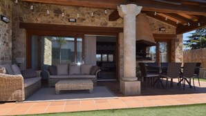Un patio al aire libre con mobiliario de mimbre, un pilar de piedra y una zona de barbacoa.