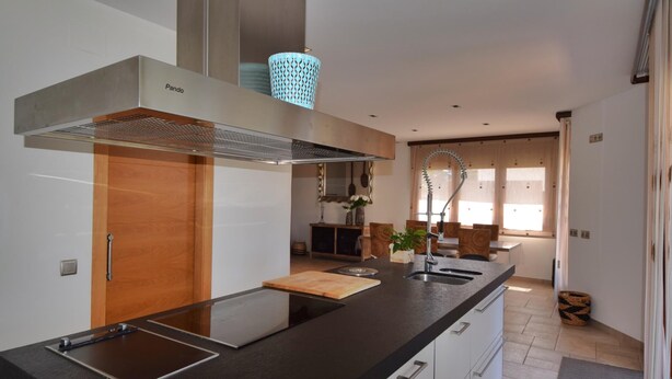 Una cocina moderna con encimera negra, electrodomésticos de acero inoxidable y puerta de madera.