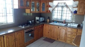 A kitchen with wooden cabinets, a stove, a microwave, and a sink. - Tranquil Ocean Views (Gros Islet)