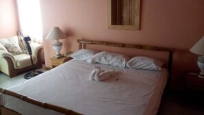A neatly made bed with white linens and pillows, a wooden headboard, and two bedside lamps on wooden nightstands. - Tranquil Ocean Views (Gros Islet)