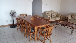 A dining area with a wooden table and chairs, a standing fan, a sofa, and a coffee table. - Tranquil Ocean Views (Gros Islet)