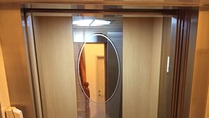 An elevator with a patterned floor, a mirror, and a phone on the wall. - Coral Habitat (Magong)