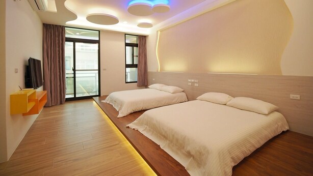 A modern hotel room with two beds, a TV, and a large window with curtains. - Coral Habitat (Magong)
