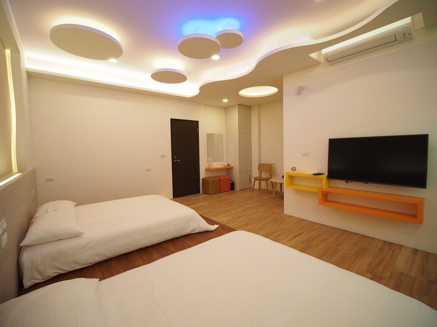 Una habitación de hotel con dos camas, televisión y baño con espejo y lavamanos.