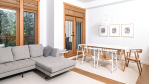 Una sala moderna con un sofá modular, una mesa de comedor con sillas y obras de arte en la pared.