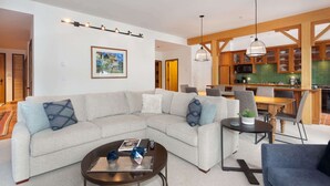 Ein modernes Wohnzimmer mit einem Ecksofa, einem Couchtisch und einem Essbereich mit Holztisch und Stühlen.