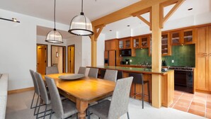 Eine moderne Küche mit Holzschränken, einer zentralen Kochinsel und einem Essbereich mit Holztisch und grauen Stühlen.