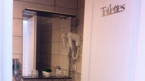 Un baño con un lavamanos blanco, un espejo y un perchero para toallas.