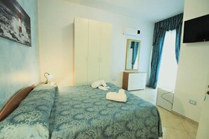 Comfortable room with a neatly made bed, wardrobe, and television.
