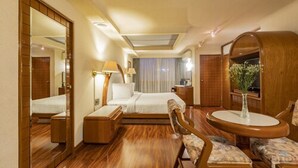 A hotel room with a bed, bedside table, chair, round table, and a mirror. - Hotel Beverly (Mexico City)