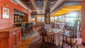 A restaurant with a bar area, wooden furniture, and large windows allowing natural light. - Hotel Beverly (Mexico City)