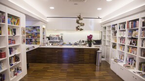 Una librería con suelo de madera, estanterías blancas y una estación de café.