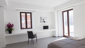Un dormitorio moderno con una cama, un escritorio con una silla, una ventana y una puerta.