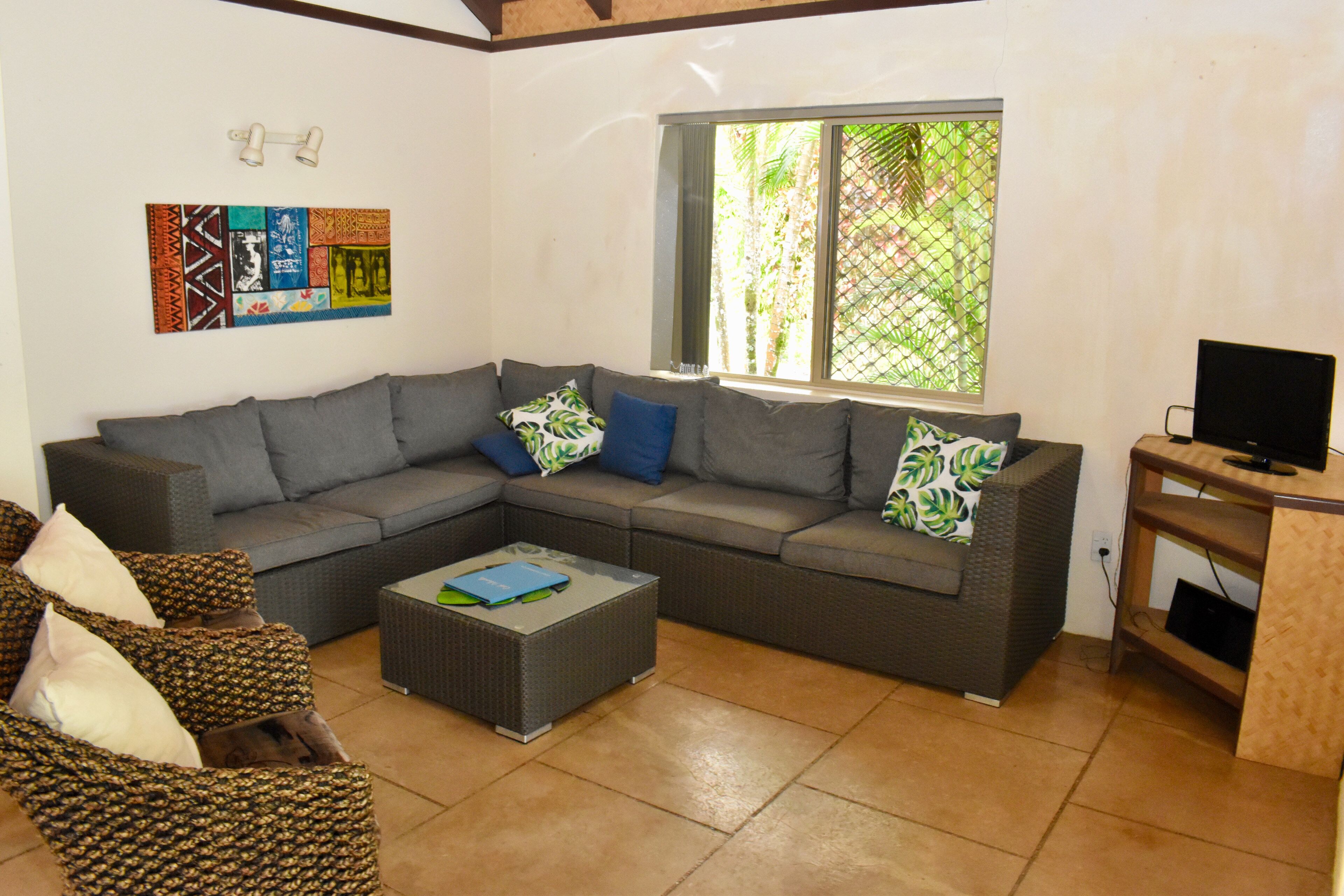 A living room with a grey sectional sofa, a coffee table, and a TV stand.