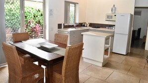 A compact kitchen with a dining area, featuring a microwave, refrigerator, and a water dispenser. - Rarotonga Island Villa 1 (Papaaroa)