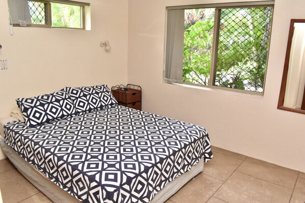 A bedroom with a bed, a window, and a small wooden box on the floor.