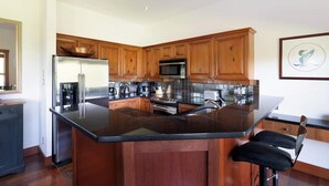 Eine moderne Küche mit Holzausstattung, Edelstahlgeräten und einer schwarzen Granit Arbeitsplatte.