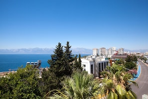 Un paisaje costero con vista despejada al mar, edificios y montañas al fondo.