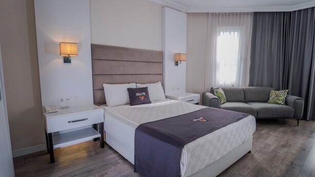 Habitación de hotel con cama, sofá, escritorio y lámpara.