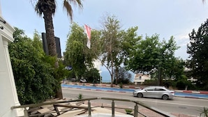 Un balcón con una mesa y sillas, con vista a una calle donde pasa un coche.