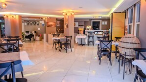 Un moderno vestíbulo de hotel con zona de bar, arreglos de asientos y un mostrador de recepción.
