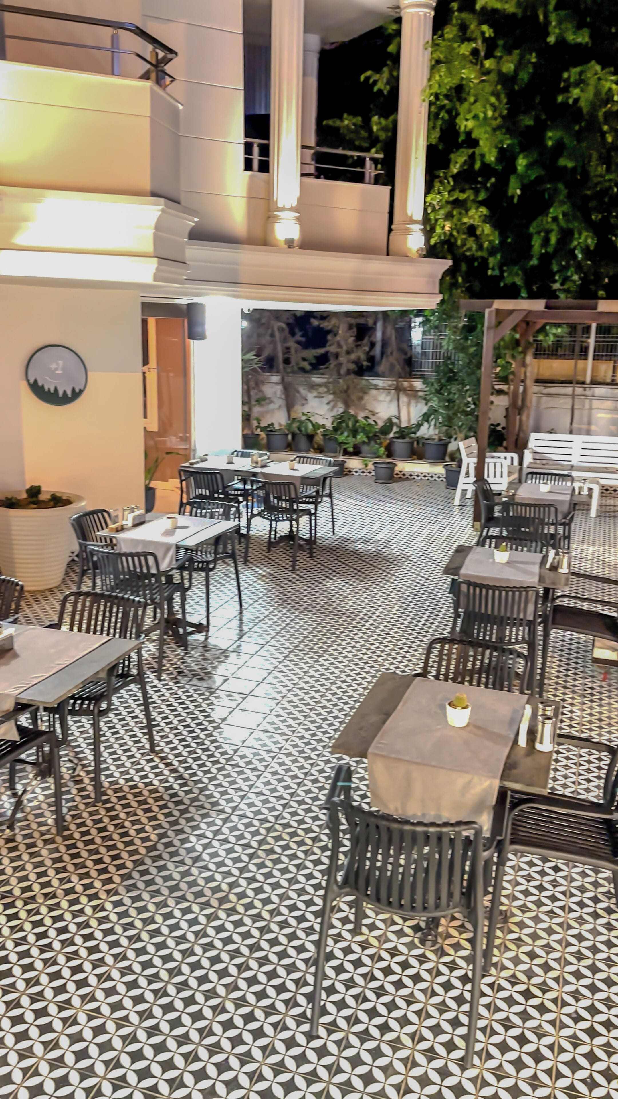 An outdoor dining area with patterned flooring, tables, and chairs.