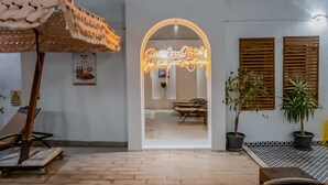 A hotel lobby with a neon sign, wooden shutters, potted plants, and a tiled floor. - Siete Hotel (Antalya)
