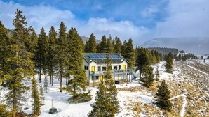 A house surrounded by snow-covered trees and a clear sky.
