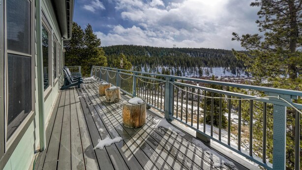 A wooden deck with a railing overlooking a forested area and a lake.