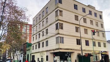 Un edificio de varios pisos con entrada a nivel de calle, un letrero visible que dice 'HOTEL' y un paso de peatones.