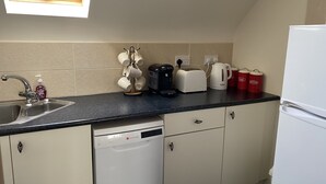 A kitchen with a dishwasher, a coffee maker, a toaster, and a kettle. - Racecourse Lodge Apartment (Clifden)