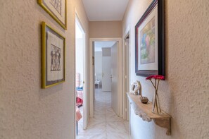 Stunning hallway with artwork and a wooden shelf, leading to a room beyond.