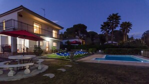 Una casa a due piani con piscina, area salotto esterna e prato curato.