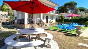 Una villa con piscina, area relax esterna e un ombrellone rosso.