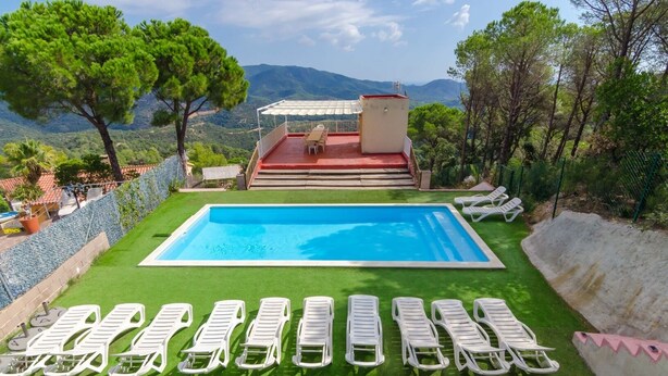 A swimming pool with lounge chairs and a patio area with a view of the mountains.
