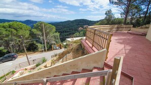 A staircase leading to a terrace with a view of a road and distant hills.