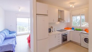 A modern kitchen with white cabinets, a built-in oven, and a washing machine.