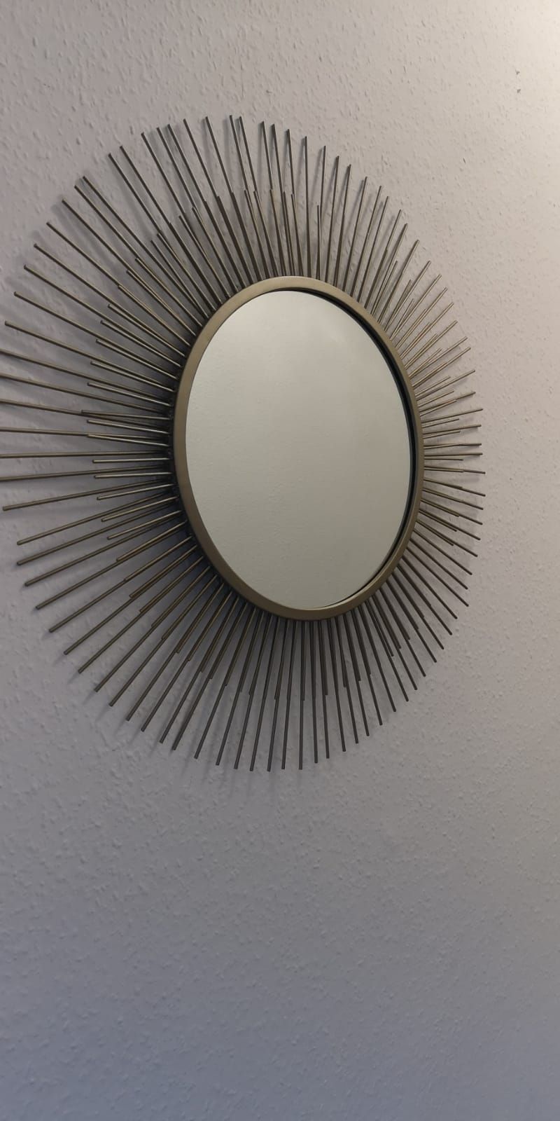 A wall-mounted mirror with a sunburst design.