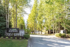 Placa do hotel 'The Aspens', com parede de pedra e vegetação.
