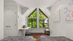 Une chambre avec deux lits, un bureau et une grande fenêtre.