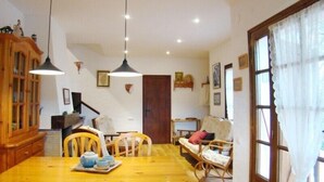 A dining area with a wooden table, chairs, and hanging pendant lights. - Club Villamar - Lovely villa for 6 persons with private swimming pool and big garden (Calonge)