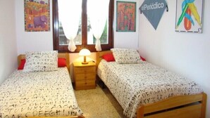 A bedroom with two beds, a nightstand, and a window with curtains. - Club Villamar - Lovely villa for 6 persons with private swimming pool and big garden (Calonge)