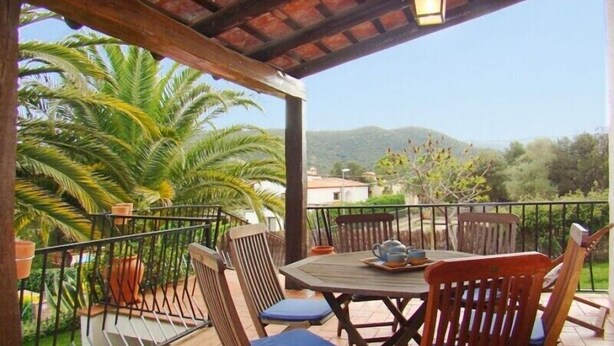 A covered patio with a table and chairs, surrounded by potted plants and a view of hills. - Club Villamar - Lovely villa for 6 persons with private swimming pool and big garden (Calonge)