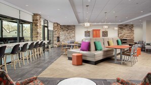 A modern lounge area with a stone fireplace, seating arrangements, and a bar counter.