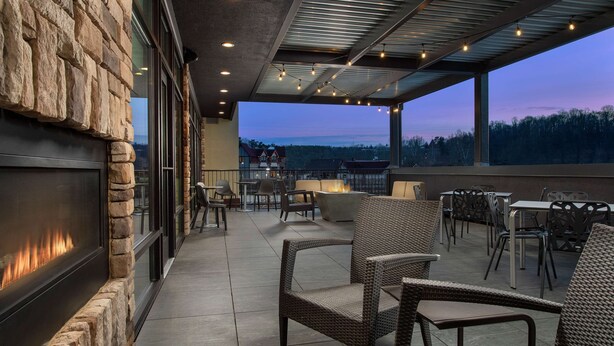 An outdoor patio with stone walls, wicker furniture, and a fire feature.